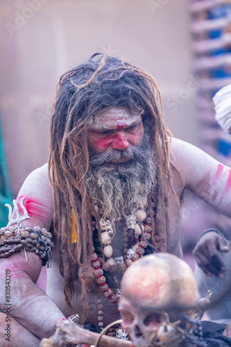 Portrait of an naga aghori sadhu holy man with pyre ash on his face and body performing aghor sadhna and smoking at harishchandra ghat in varanasi.	