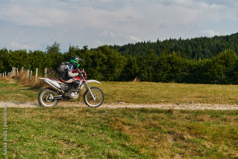 A professional motocross rider exhilaratingly riding a treacherous off-road forest trail on their motorcycle.