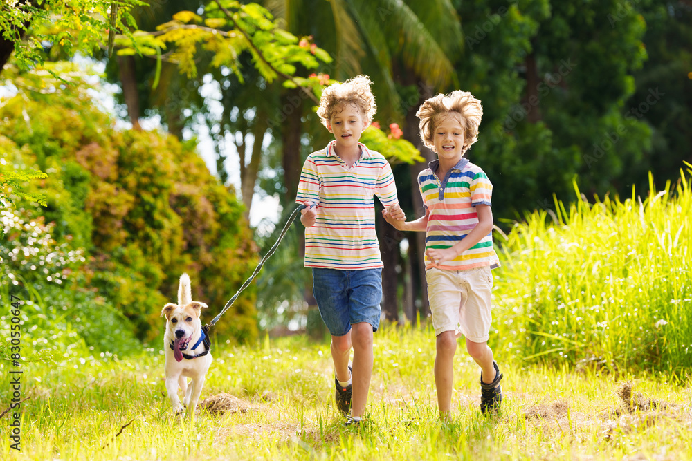 Obraz premium Kids play with dog. Children and puppy run in park