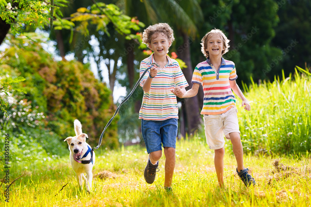 Obraz premium Kids play with dog. Children and puppy run in park