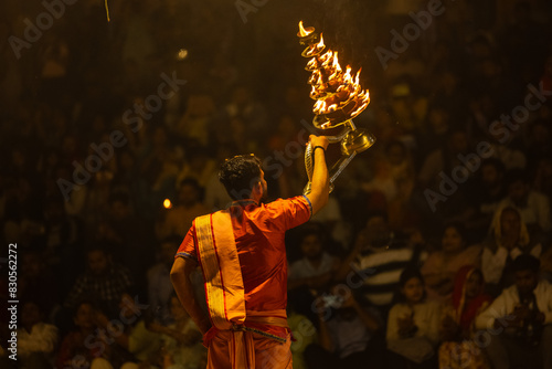 Ganga aarti, Portrait of young priest performing holy river ganges evening aarti at assi ghat in traditional dress with hindu rituals.	