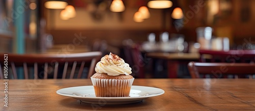 A close up copy space image of a cupcake with a fork sitting on a wooden coffee shop table during a holiday
