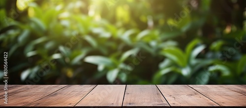 A wooden table on a deck with a background of blurred foliage creates a copy space image