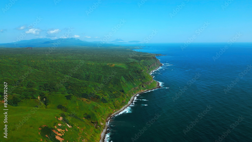 Green fields, meadows, summer blue sky and calm sea. Clip. Picturesque countryside marine landscape with green forested cliffs.