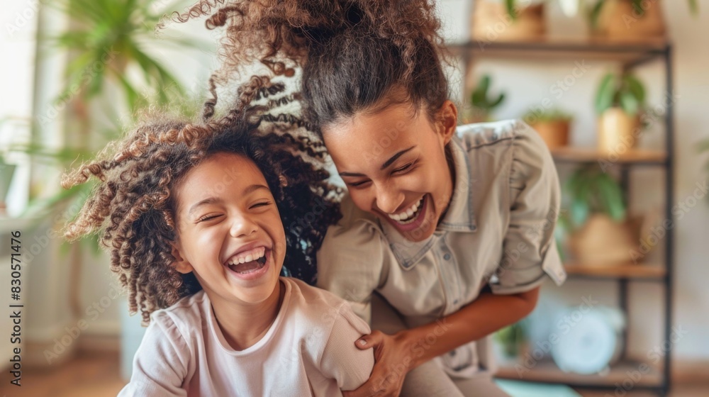 A woman and a young girl are laughing and smiling together in a living room. Scene is happy and joyful A woman and a young girl are laughing and smiling together in a living room. Scene is happy and joyful