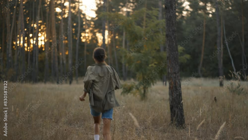 beautiful happy woman in casual wears joyfully runs in fall forest between golden spikelets of tall dry grass. romantic girl relaxing in magic autumn forest with wonderful sunlight beautiful happy woman in casual wears joyfully runs in fall forest between golden spikelets of tall dry grass. romantic girl relaxing in magic autumn forest with wonderful sunlight