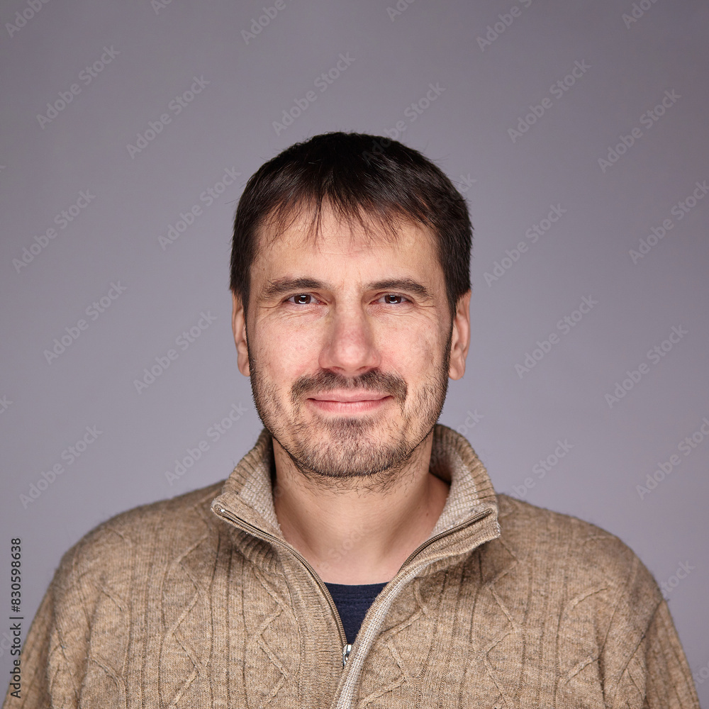 Fototapeta premium A man smiles warmly and confidently at the camera in a studio setting, radiating happiness and self-confidence.