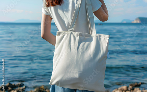 Close up woman holding fabric tote bag on a seaside Woman Holding Fabric Tote Bag at the Beach