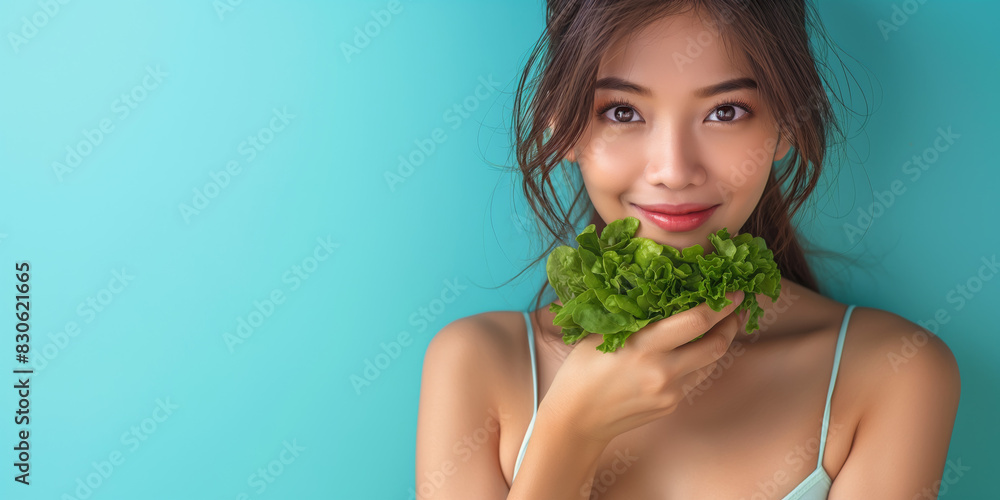 Smiling woman holding fresh green lettuce against a turquoise background, promoting healthy eating and an organic lifestyle. Smiling woman holding fresh green lettuce against a turquoise background, promoting healthy eating and an organic lifestyle.