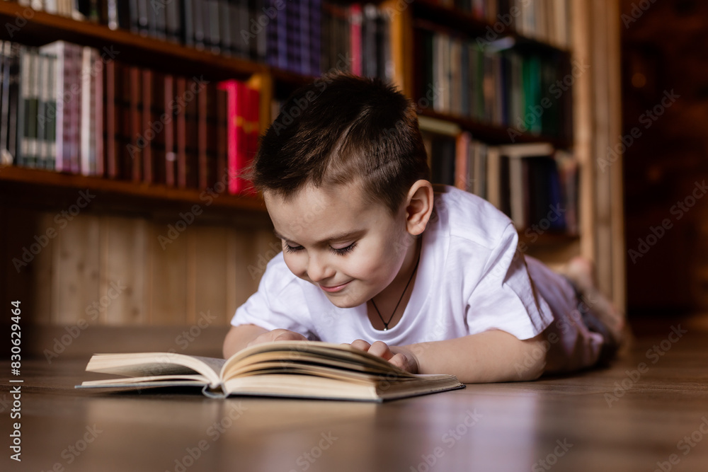 little boy is reading a book in the library at home little boy is reading a book in the library at home