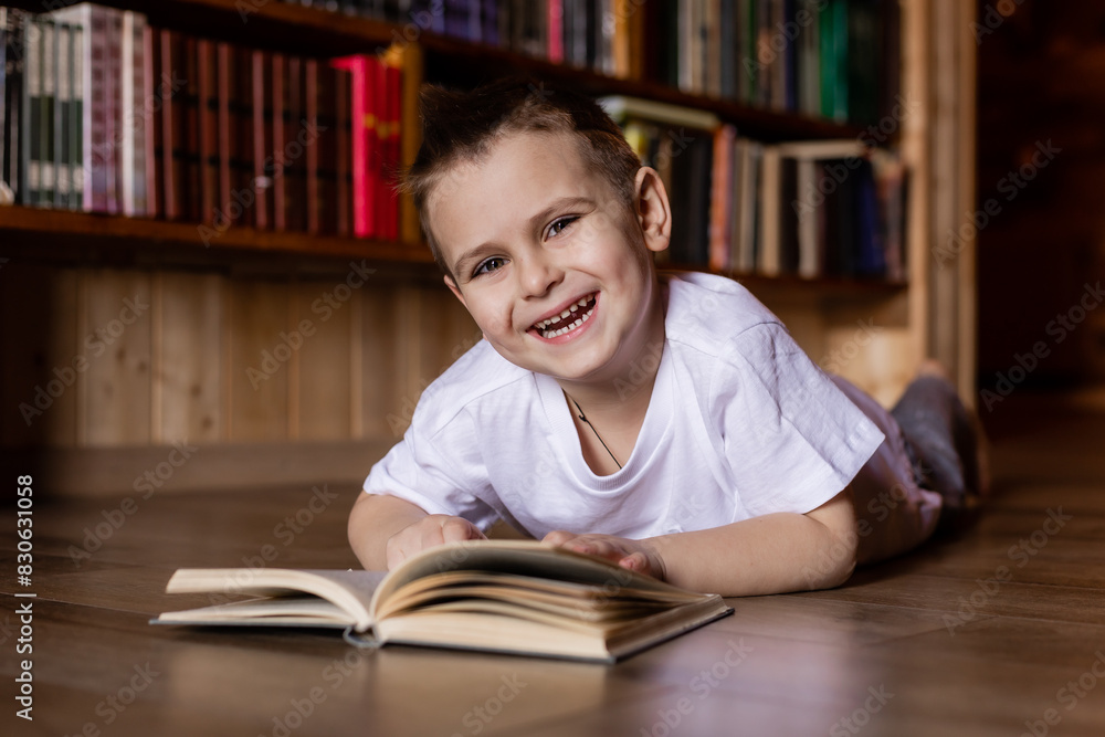 little boy is reading a book in the library at home little boy is reading a book in the library at home