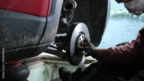 Сar mechanic replaces an old brake disc with a new one in a car repair service