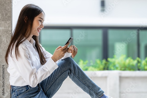 Image of young pleased happy cheerful cute beautiful business asia woman sit indoors in office using laptop computer listening music with earphones.