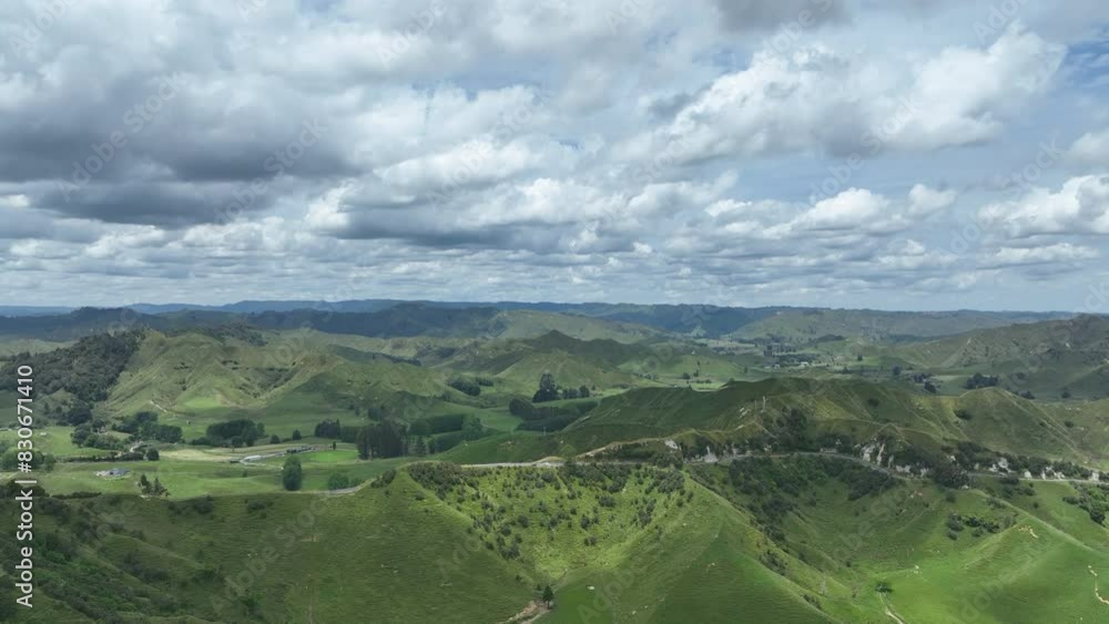 A cloudy summers day flight across the rolling foothills of Taranaki province in Aotearoa New Zealand. The famous tourism route Forgotten World Highway rises up a steep hillside to reach the crest. A cloudy summers day flight across the rolling foothills of Taranaki province in Aotearoa New Zealand. The famous tourism route Forgotten World Highway rises up a steep hillside to reach the crest.