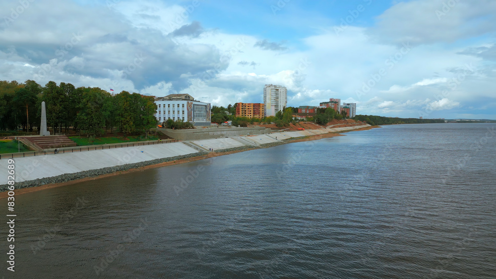 Top view of river embankment of city with forest. Clip. Landscaped embankment of city river bank. Beautiful landscape of river embankment with city park