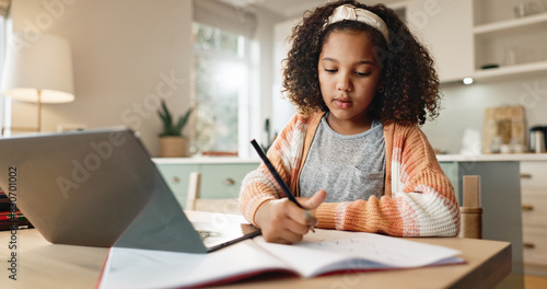 Tableau sur toile Girl child, education and writing with laptop for online learning in home, digital application and literature for growth or development