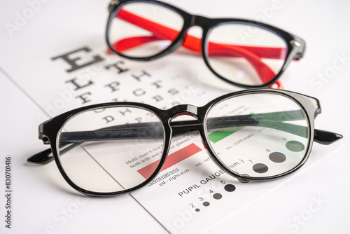 Glasses on eye testing exam chart to check eyesight accuracy of reading.