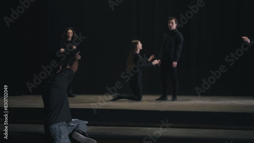 Wallpaper Mural Rear view of a confident male director with papers in his hands waving his arms and gesticulating showing the actors how to play correctly during a rehearsal of actors in black suits on stage in the Torontodigital.ca