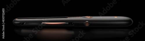 Close-up of a sleek, modern hair straightener with a black finish and orange accents, isolated against a black background. photo