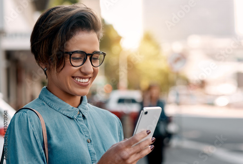 Business woman, phone and reading in city for travel news, location or communication of job opportunity. Excited young worker, editor or copywriter in glasses with mobile chat for transport in street