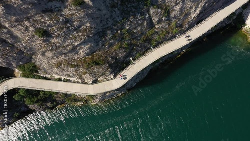 Garda bike path. Bicycle/pedestrian path Garda suspended above the lake. Alley of Limone sul Garda. Section of the longest cycle path in Europe 4K aerial view.
