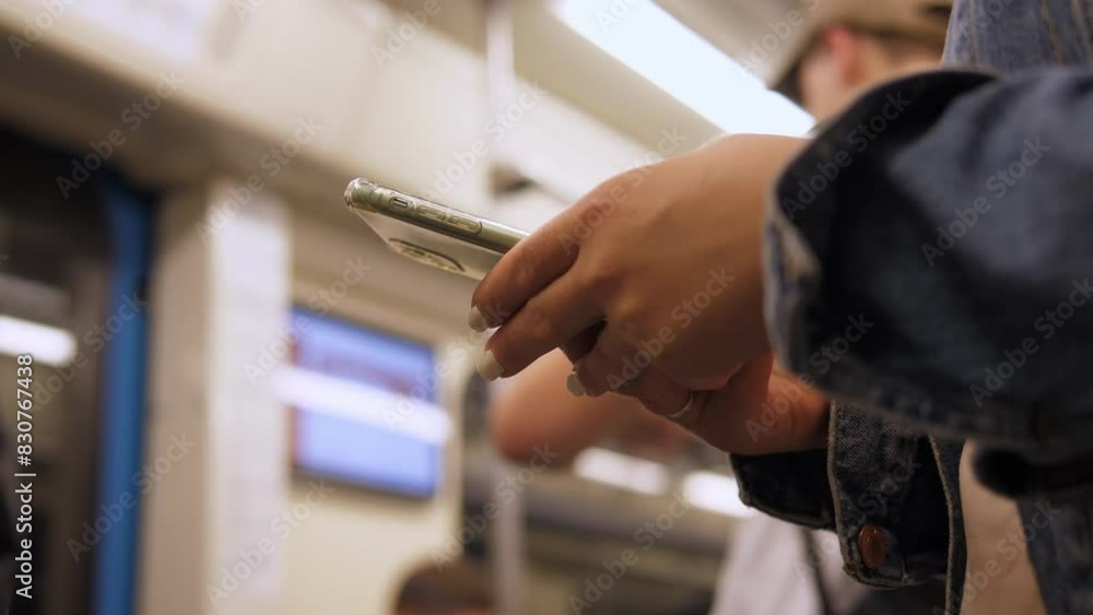 Hands of a woman using a smartphone in a crowded train car in the subway close-up. A girl in the subway searches for information on the Internet, reads, studies online or sends text messages. Hands of a woman using a smartphone in a crowded train car in the subway close-up. A girl in the subway searches for information on the Internet, reads, studies online or sends text messages.