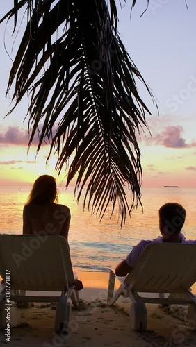 Couple on the tropical beach are admiring the sunset.