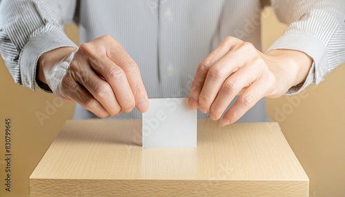 選挙の投票箱に投票用紙を入れようとする男性の手もと。