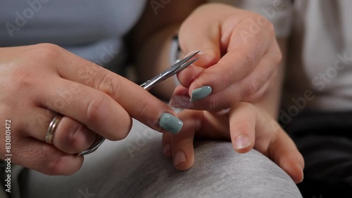 Close-up of a mother cutting her little son's nails with nail scissors at home. Taking care of the child. 