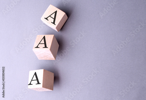 AAA word on wooden block on gray background photo