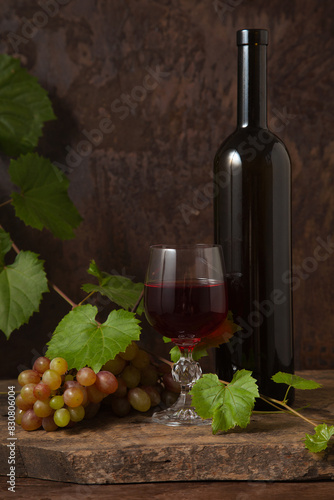 Still life with glass of red wine and grapes on vintage wooden background..