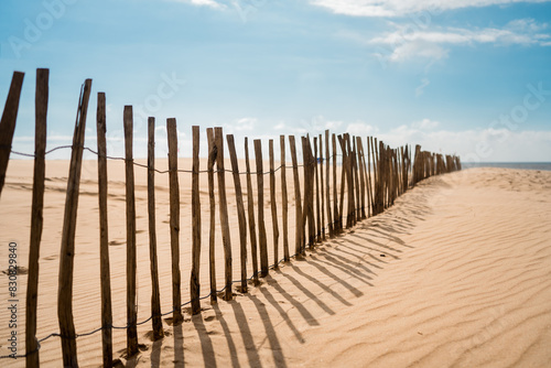 Rustic Wooden Fence on a Sandy Beach under a Clear Blue Sky, Coastal Barrier for Sand Dune Protection