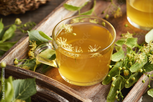 A transparent cup of herbal tea with fresh linden or Tilia cordata flowers