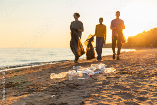 Earth day. Volunteers activists team collects garbage cleaning of beach coastal zone. Woman mans with trash in garbage bag on ocean shore. Environmental conservation coastal zone cleaning