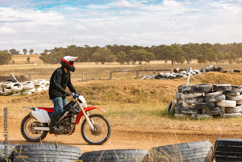 Teen boy riding motorbike at motocross track meet photo