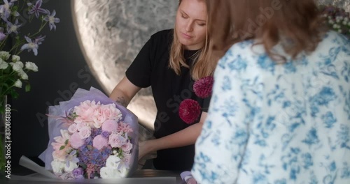 The florist wraps the bouquet in decorative paper in the flower shop