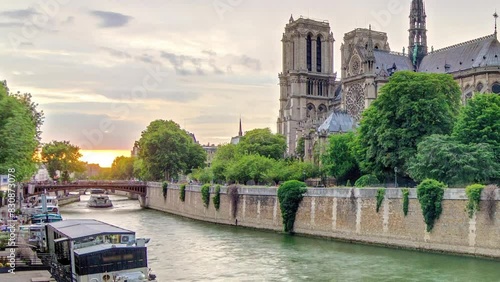 Sunset behind cathedral Notre Dame de Paris timelapse in Paris, France. View from bridge of the Archbishopric. Boat station and waterfront. Architecture and landmarks of Paris with dramatic sky. photo