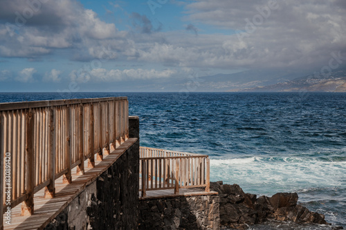 A wooden walkway leads to the ocean. The water is calm and the sky is cloudy