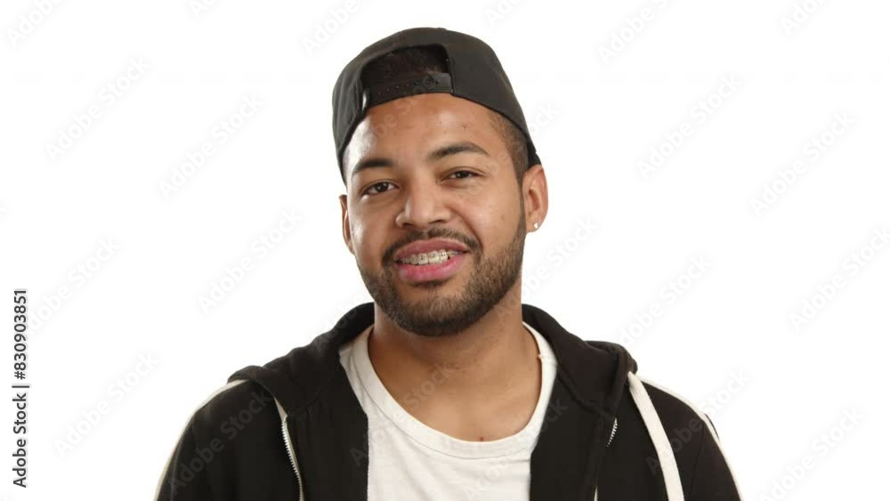 A welcoming and cheerful young Afro-American man stands with his arms confidently crossed, sporting a cap and a relaxed smile, isolated on a white background. Camera 8K RAW. A welcoming and cheerful young Afro-American man stands with his arms confidently crossed, sporting a cap and a relaxed smile, isolated on a white background. Camera 8K RAW.