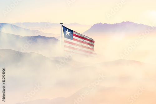 Liberia flag disappears in beautiful clouds with fog. photo