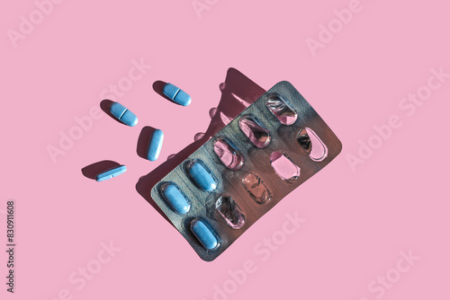 Blue pills and blister pack over pink background