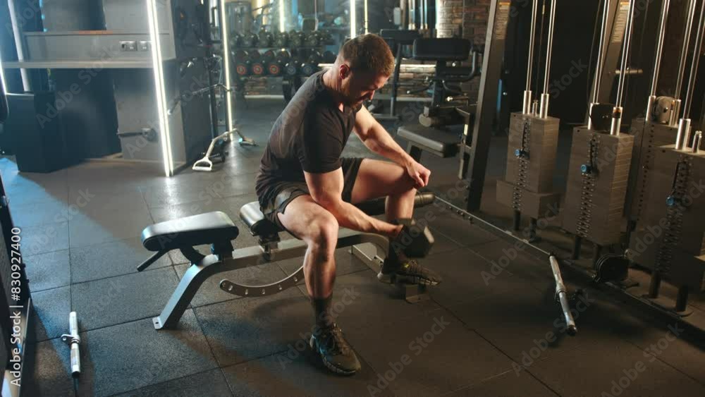In a gym, a strong man, sitting on a weightlifting bench, does bicep curls with dumbbells, displaying focus and dedication. Its an intense workout session showcasing his strength training In a gym, a strong man, sitting on a weightlifting bench, does bicep curls with dumbbells, displaying focus and dedication. Its an intense workout session showcasing his strength training