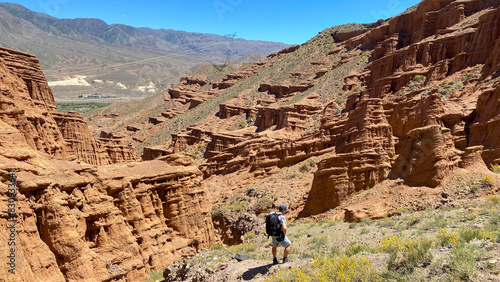 Walking through the canyons is like a car wash. A man walks through the desert with a backpack on his shoulders. Travel to Kyrgyzstan