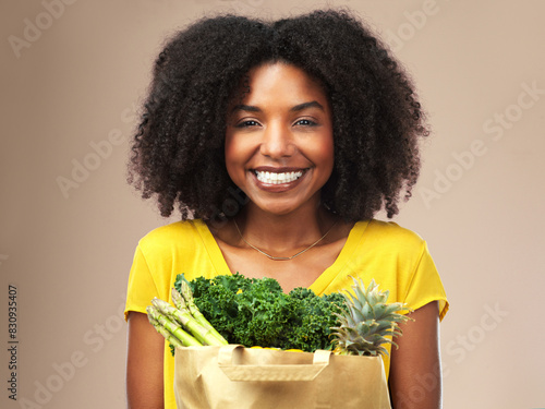 Black woman  portrait and grocery package of vegetables or fruit in studio background smiling for health food. Happy  female person or nutritionist with bag for wellness  organic shopping and