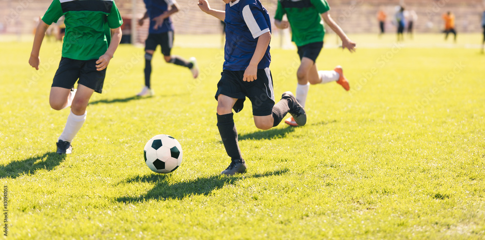 Happy kids compete in football game. Running soccer players. Competition between players running and kicking football ball. Football school. Young boys playing soccer game. Kids having fun in sport. Happy kids compete in football game. Running soccer players. Competition between players running and kicking football ball. Football school. Young boys playing soccer game. Kids having fun in sport.