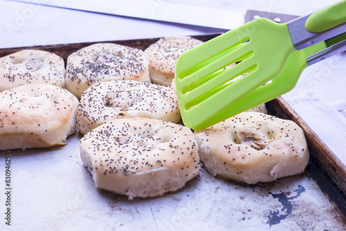 Baker removes pletzalej with silicone tongs from a steel tray