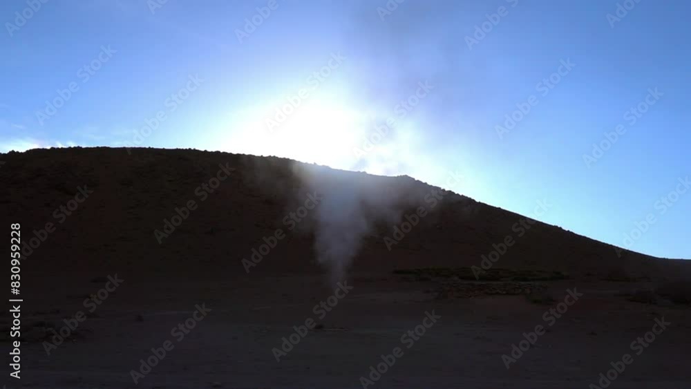 Lockdown Shot Of Smoke Emitting From Active Volcanic Geyser By Rock Formation Against Clear Sky - Uyuni, Bolivia Lockdown Shot Of Smoke Emitting From Active Volcanic Geyser By Rock Formation Against Clear Sky - Uyuni, Bolivia