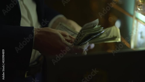 Business professional handling money in dark room, focusing on financial transactions photo