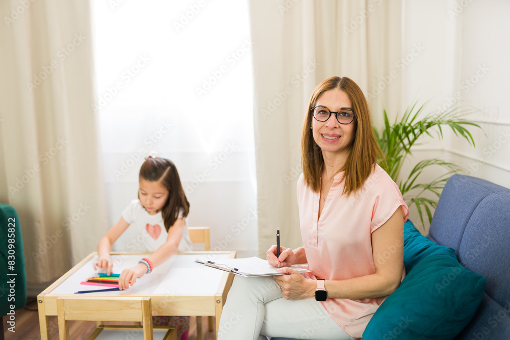 Child psychologist smiles and makes eye contact while working with a little girl in therapeutic activities during session Child psychologist smiles and makes eye contact while working with a little girl in therapeutic activities during session