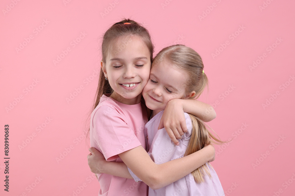 Portrait of cute little sisters on pink background Portrait of cute little sisters on pink background